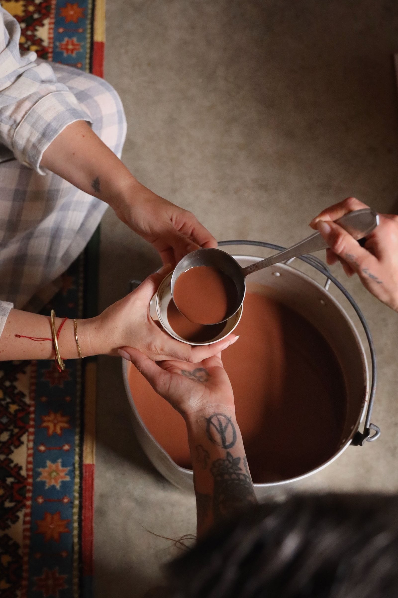 Ceremonial cacao being ladled into a cup held in open hands