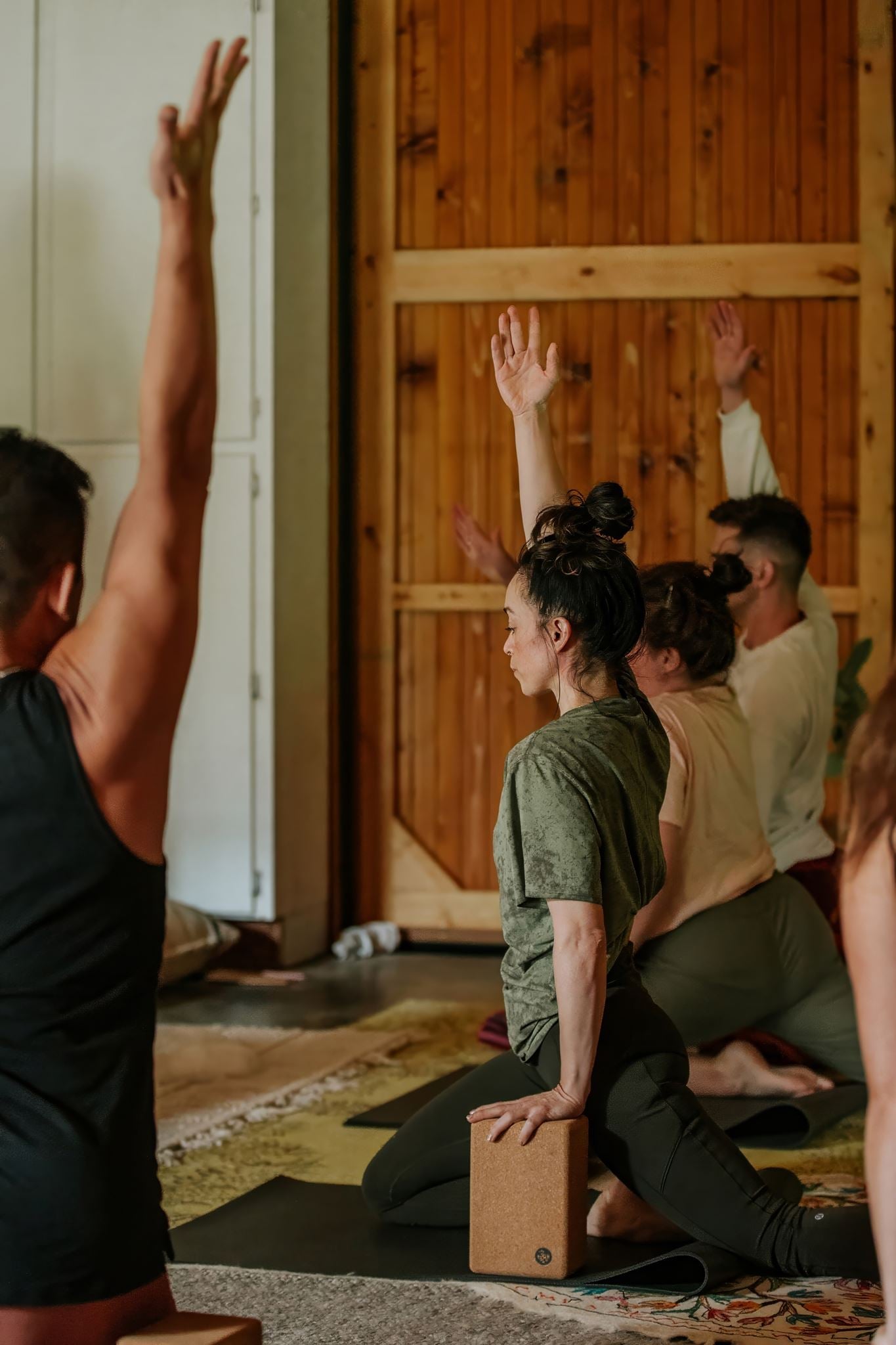 A yoga class in the barn, arms raised overhead