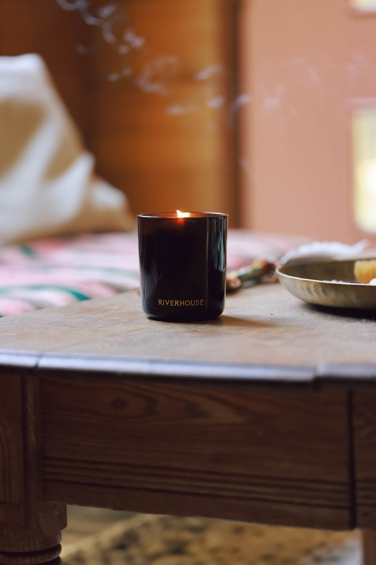 A lit Riverhouse candle on an old wooden table