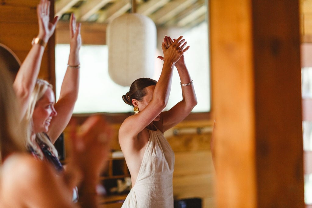 Women with arms raised overhead in the barn