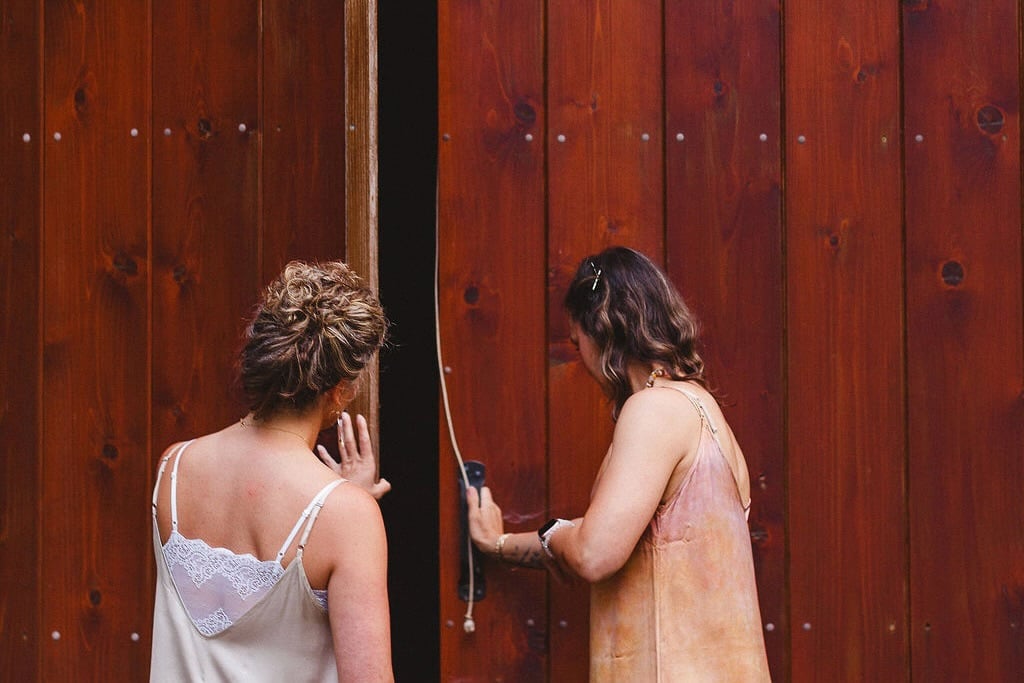 Two women opening the red barn doors