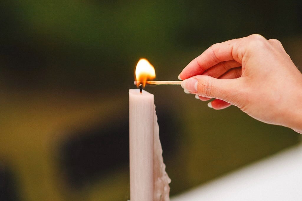 A match lighting a pale taper candle