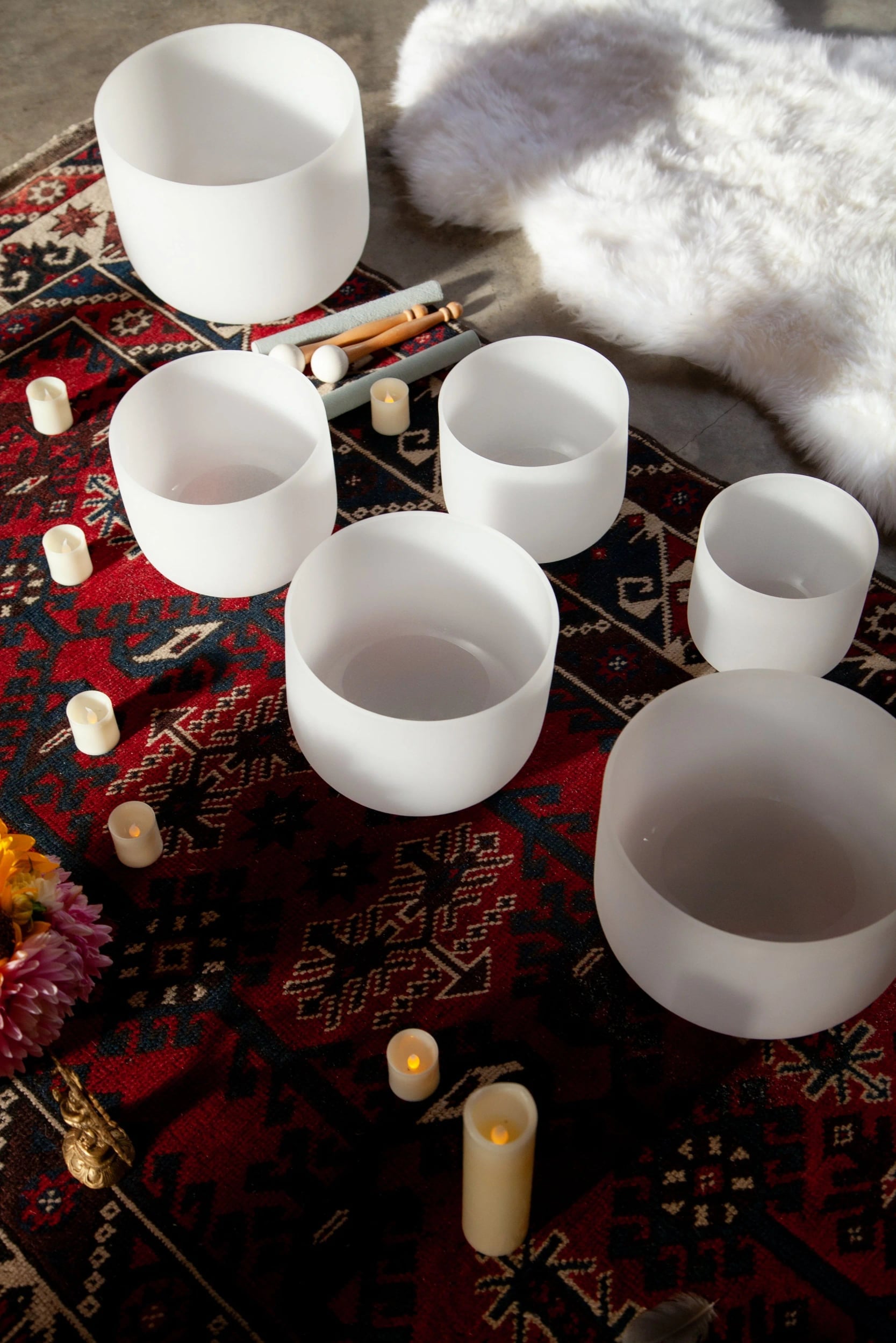 Crystal singing bowls and candles on a red rug