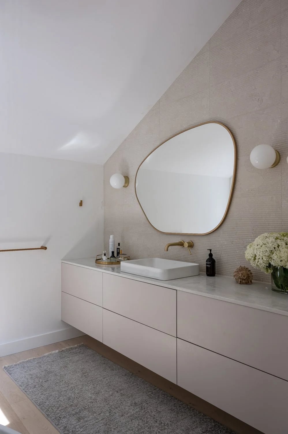A curved mirror above a long white vanity