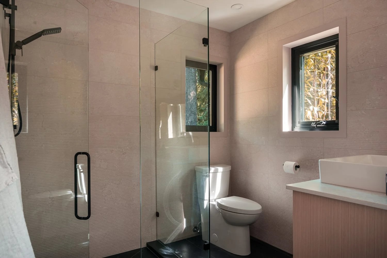 A pale pink bathroom with a glass shower