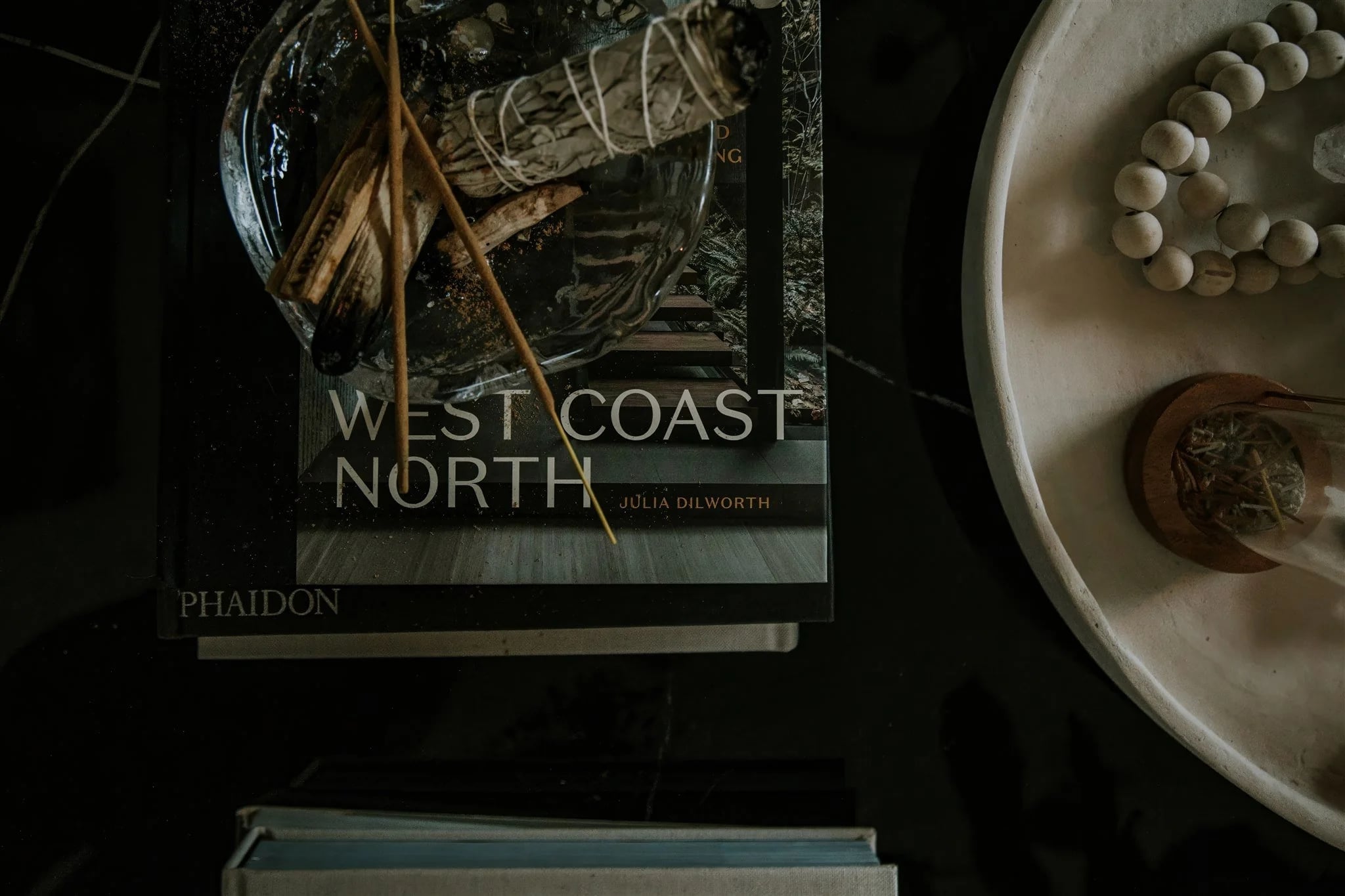 Coffee-table books and a dish of beads in low light