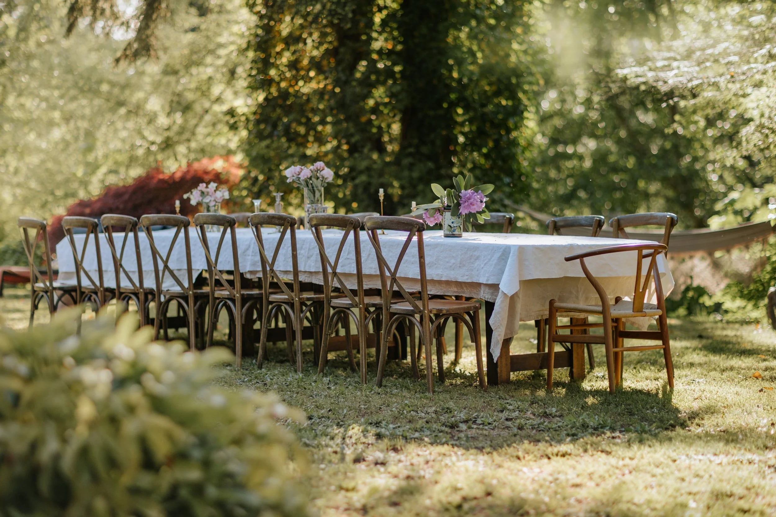A long table set with white linen on the lawn