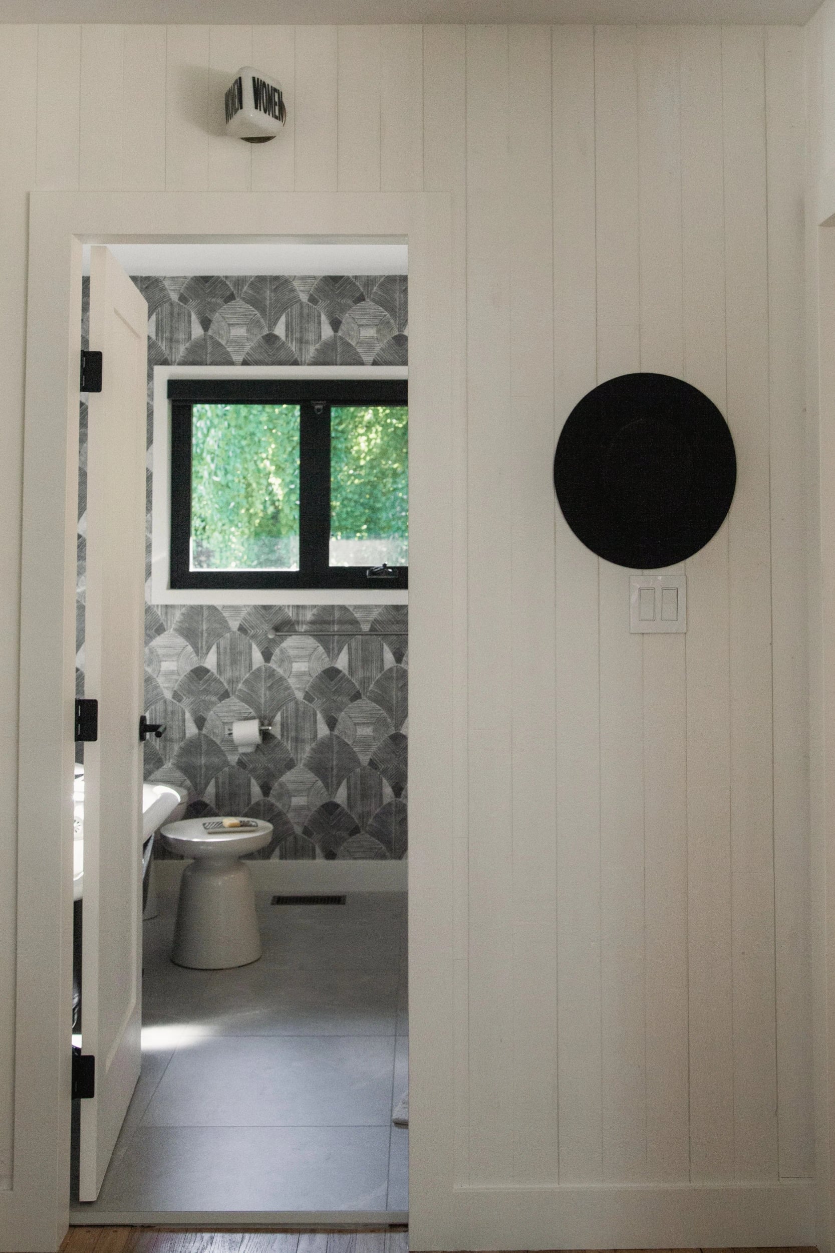 A white door opening onto a patterned-tile washroom