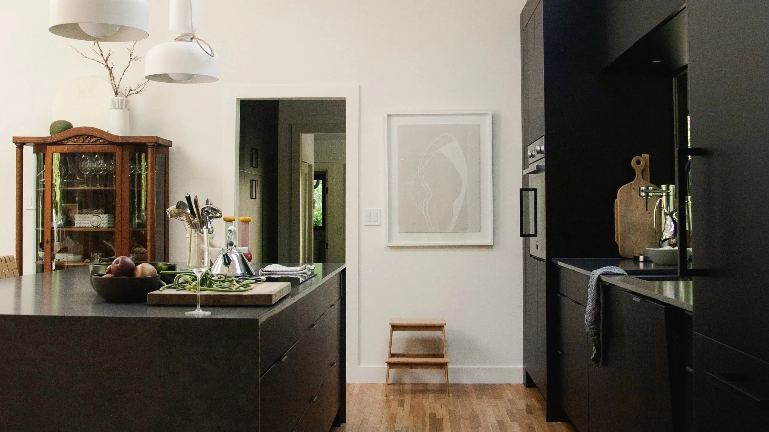 A dark kitchen island and white walls with a vintage cabinet