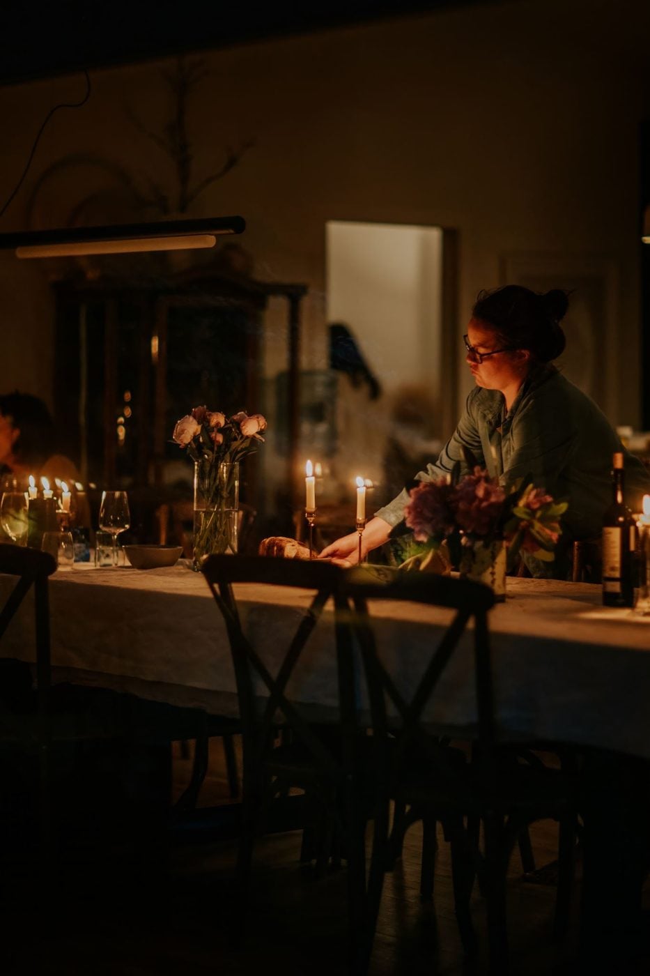 A long candlelit table being set for dinner