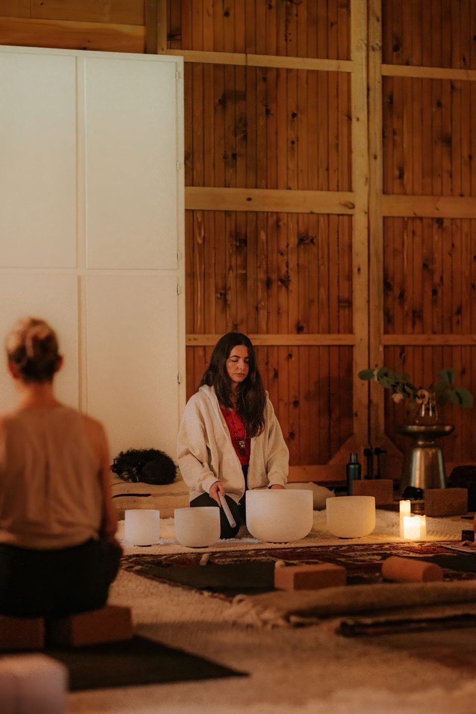 A woman playing crystal singing bowls in the barn